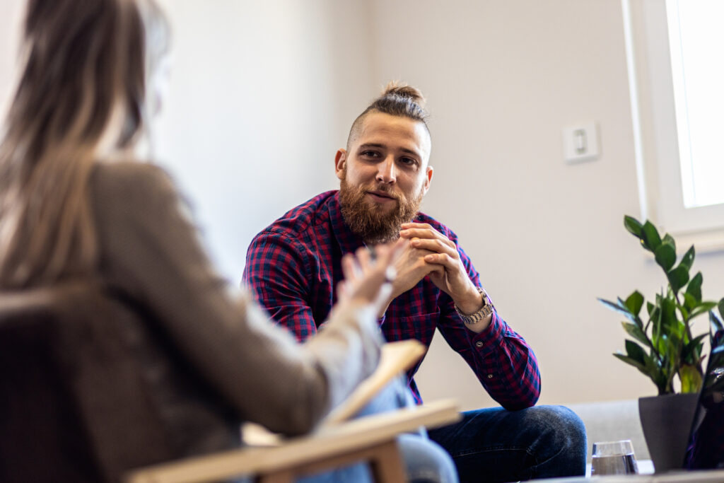 Woman psychologist talking to a young man during a trauma treatment center