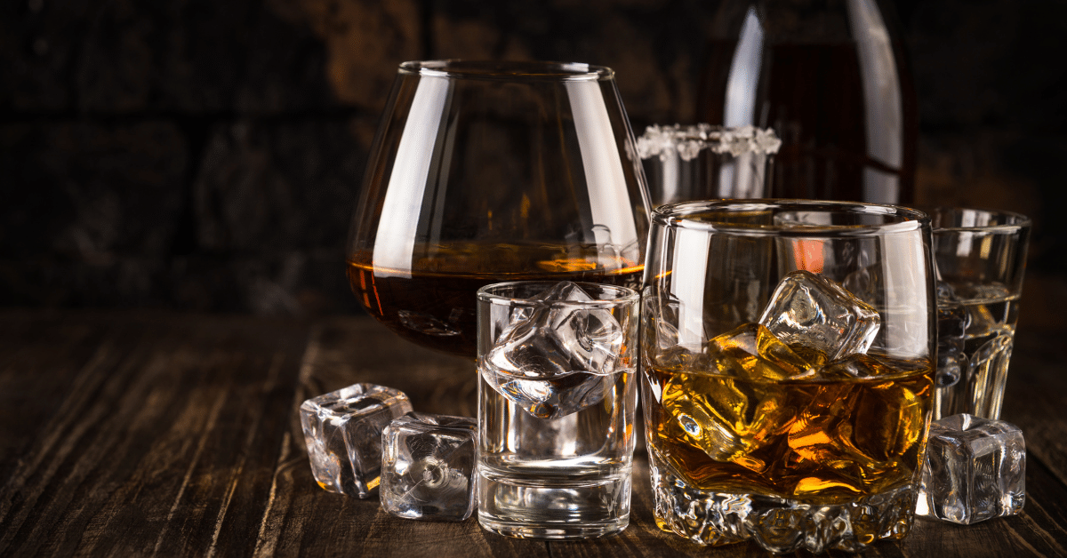 Glasses of alcohol with ice on a wooden table.