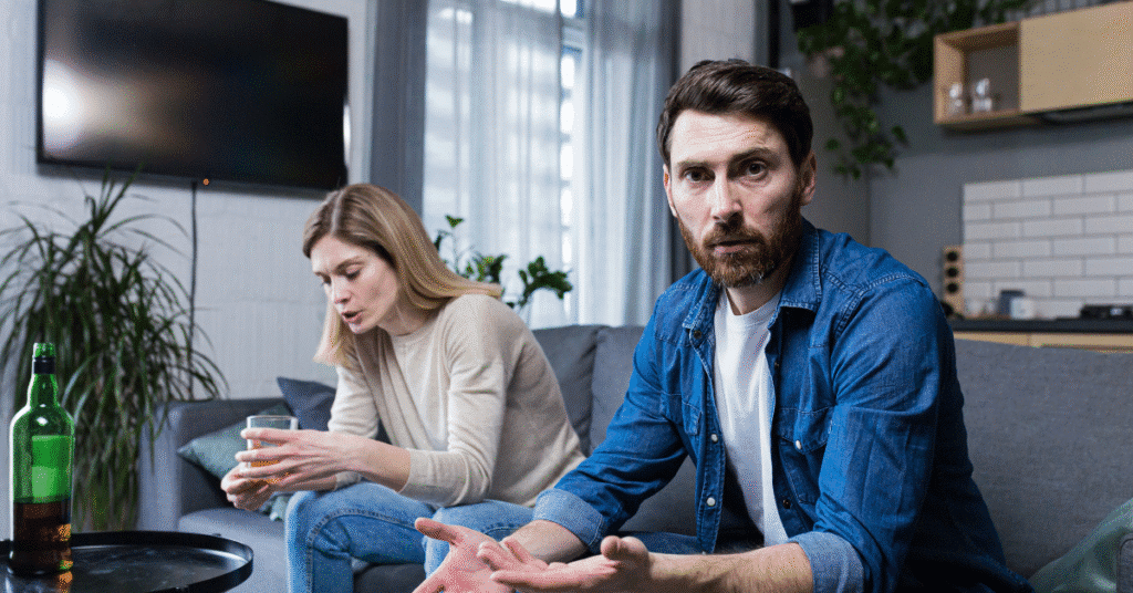 A tense moment between a couple, with one holding a drink and the other expressing concern