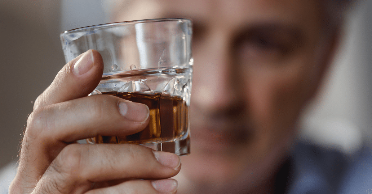 Close-up of a man holding a glass of whiskey