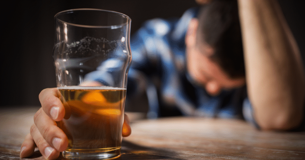 Man holding a glass of beer with head down