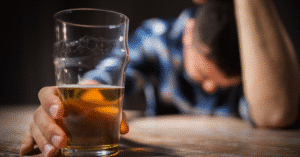 Man holding a glass of beer with head down