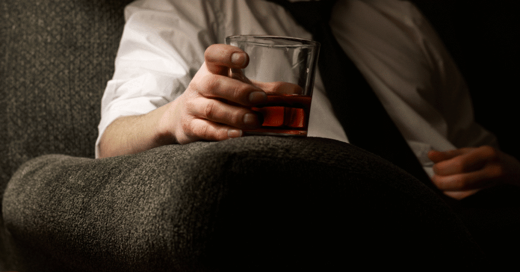 Man holding a glass of whiskey at night