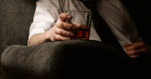 Man holding a glass of whiskey at night