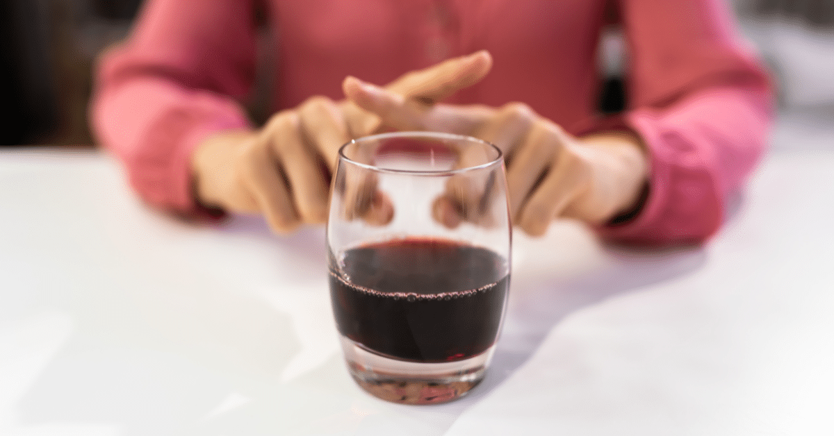 Person refusing a glass of red wine.