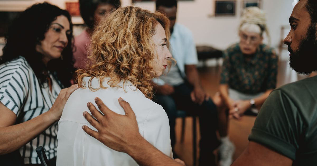 Support group comforting a distressed woman