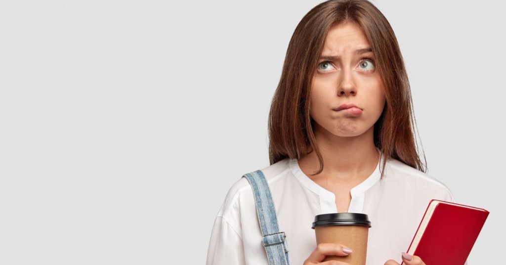 Confused woman holding coffee and notebook