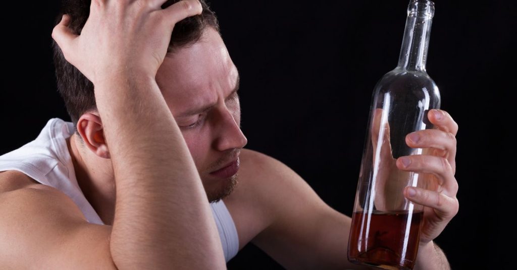 Distressed man holding alcohol bottle