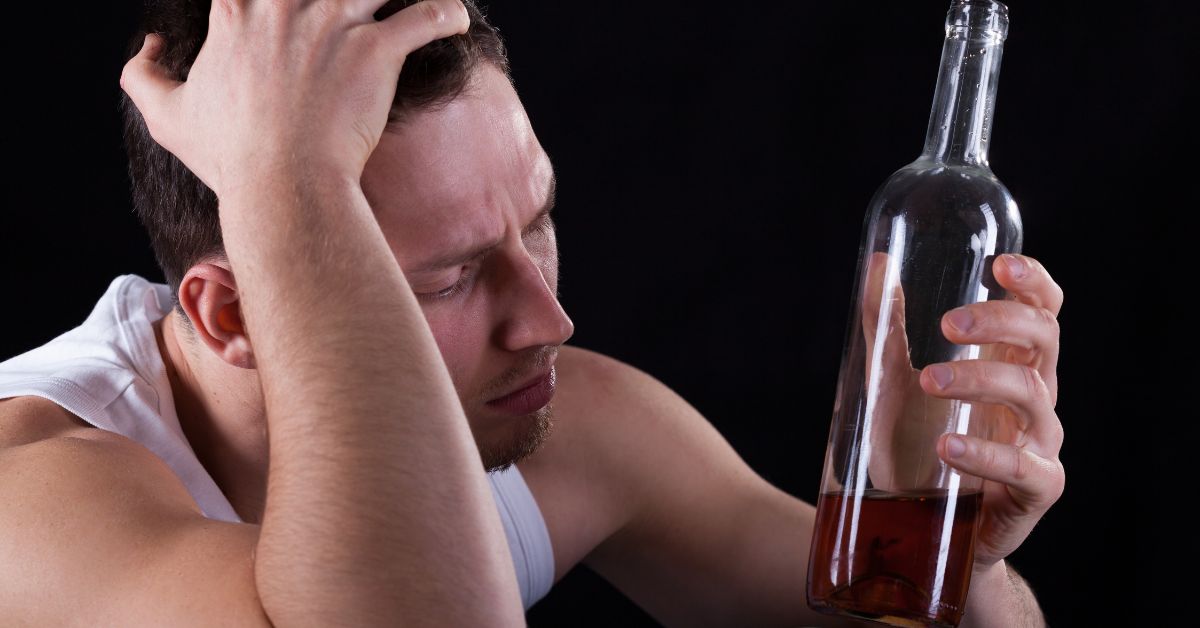 Distressed man holding alcohol bottle