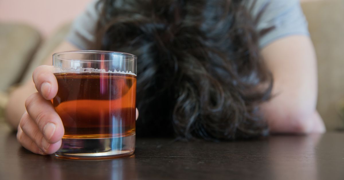 Person holding alcohol glass, head down