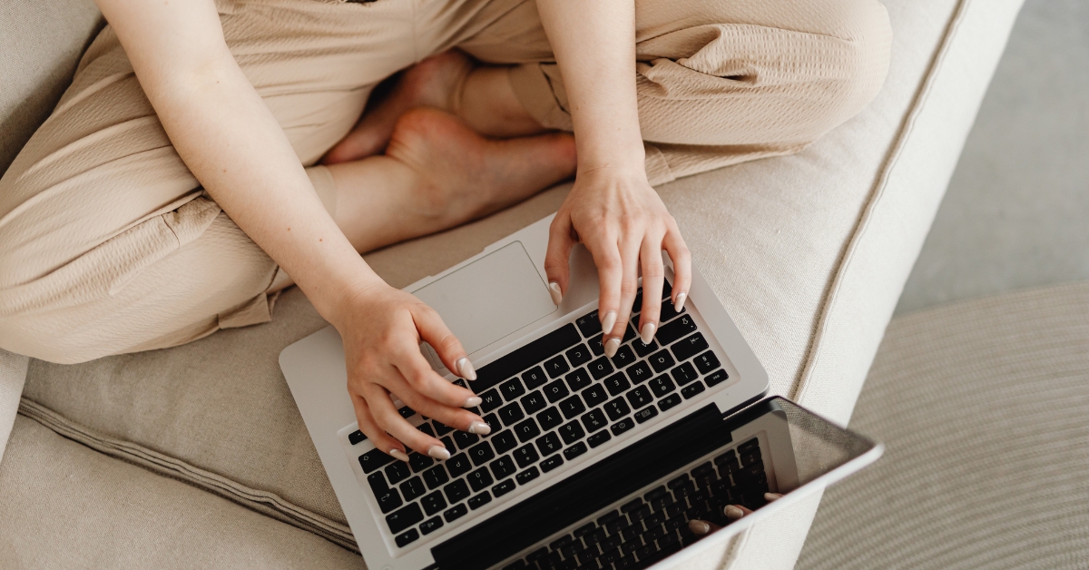 Person typing on laptop on couch