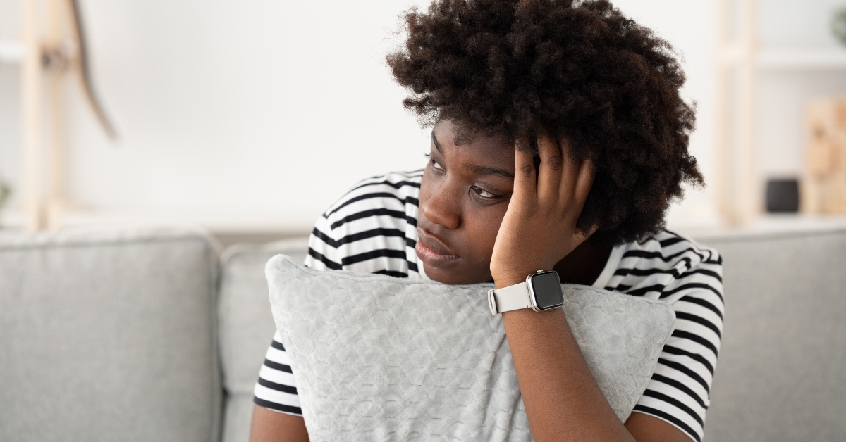 Woman looking stressed while sitting on couch