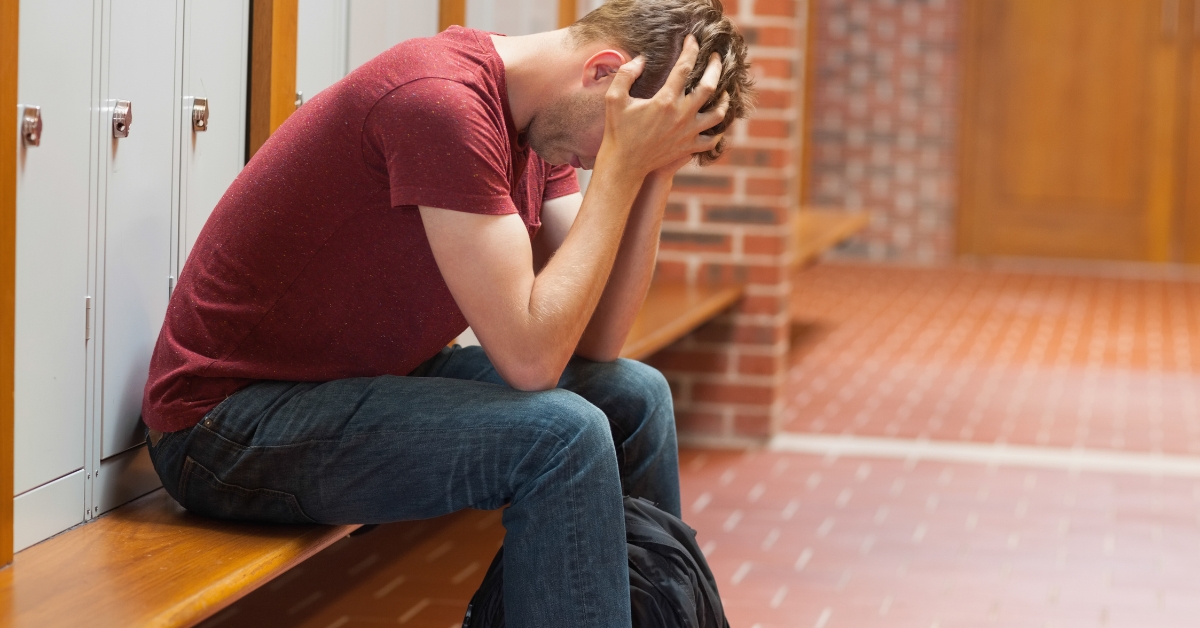 Young man sitting distressed in locker room