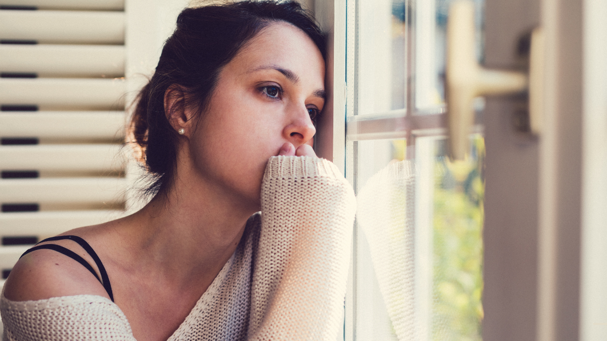 Homepage 5 Woman leaning against a window looking withdrawn, a common sign of depression