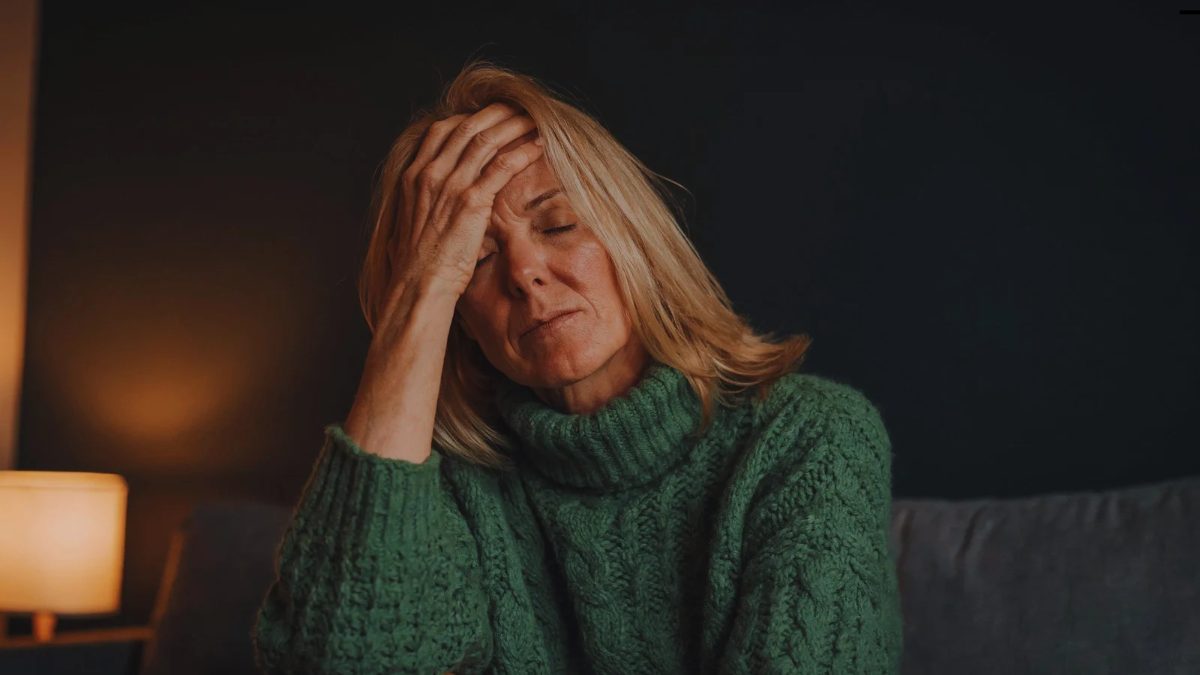 Homepage 5 Woman with her hand on her forehead, eyes closed, looking exhausted on a sofa at home